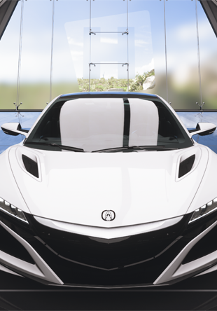 White Acura NSX supercar viewed from front angle, showcasing sleek modern design with sharp LED headlights, wide aerodynamic stance, and low-slung profile characteristic of high-performance vehicles